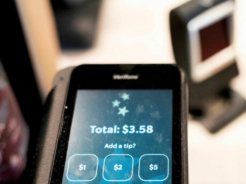caption: Tip options are displayed on a card reader at a store in Washington, D.C., on March 17, 2023.