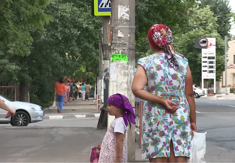 caption: A woman and child stand on a street corner in Moldova. 