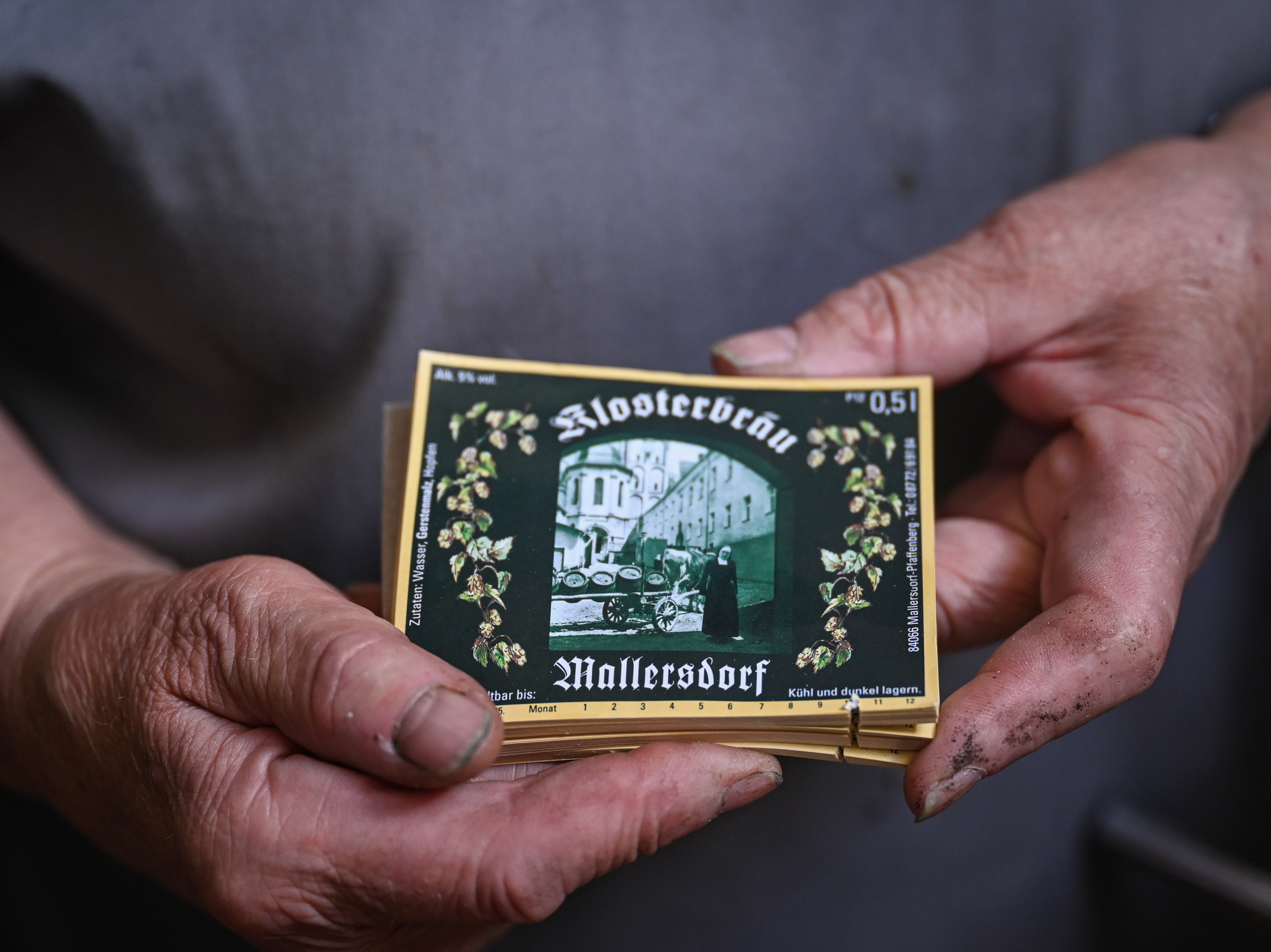 caption: Sister Doris holds labels of the beer bottles with a painting of the former nun who was running the brewery.