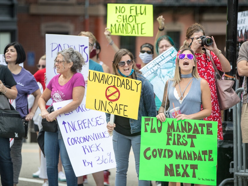 caption: Anti-vaccine activists protested at the Massachusetts State House in August against Governor Charlie Baker's mandate that all students enrolled in child care, pre-school, K-12, and post-secondary institutions must receive the flu vaccine this year.
