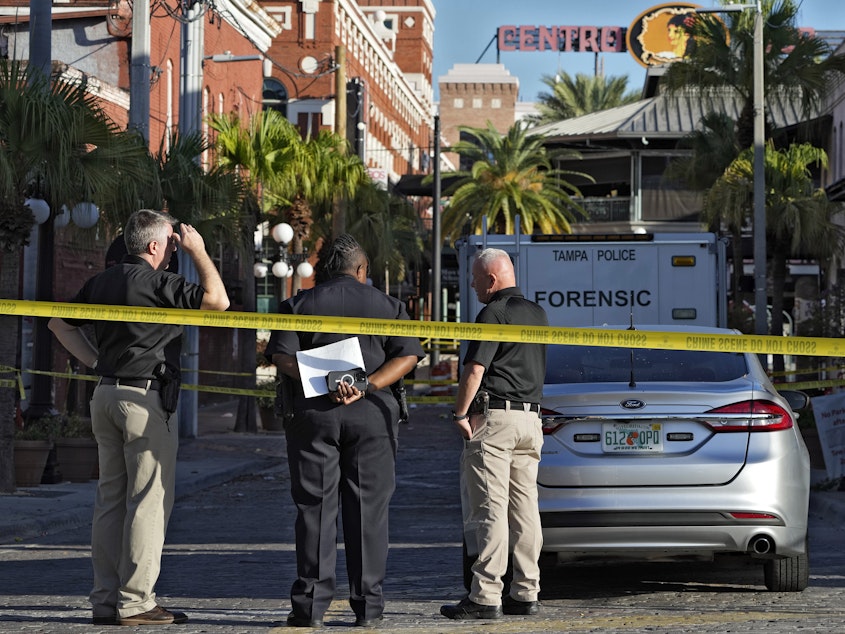 caption: Tampa police officers stand in the street in the Ybor City section of Tampa, Fla., after a shooting early Sunday. A fight between two people turned deadly in a shooting during Halloween festivities.