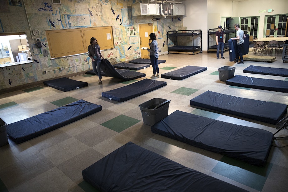 caption: Volunteers set up sleeping mats at ROOTS Young Adult Shelter on Tuesday, July 10, 2018, in Seattle. The shelter can accommodate up to 45 young adults a night.