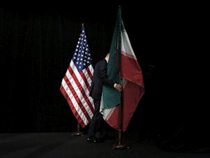 caption: A staff person removes the Iranian flag from the stage after a group picture with representatives of the United States, Iran, China, Russia, Britain, Germany, France and the European Union during the Iran nuclear talks in July 2015 in Vienna.