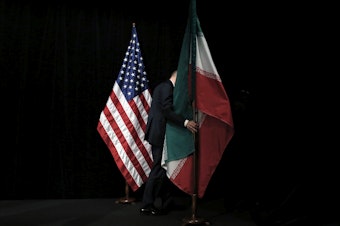 caption: A staff person removes the Iranian flag from the stage after a group picture with representatives of the United States, Iran, China, Russia, Britain, Germany, France and the European Union during the Iran nuclear talks in July 2015 in Vienna.