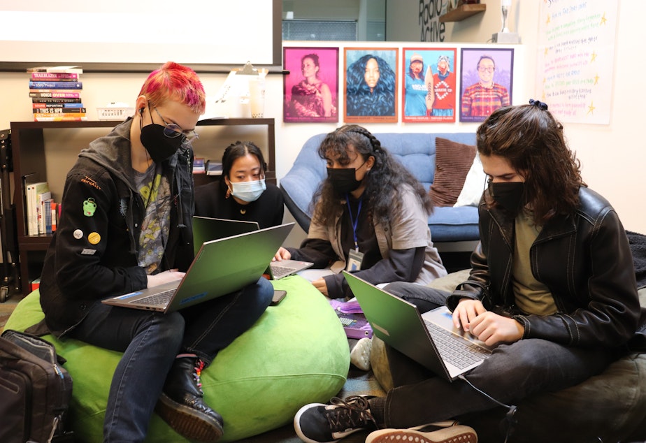 caption: Gideon Hall, Dayana Capulong, Terina Papatu and Dash Pinck work on their stories in the RadioActive programming space at KUOW on February 25, 2023.
