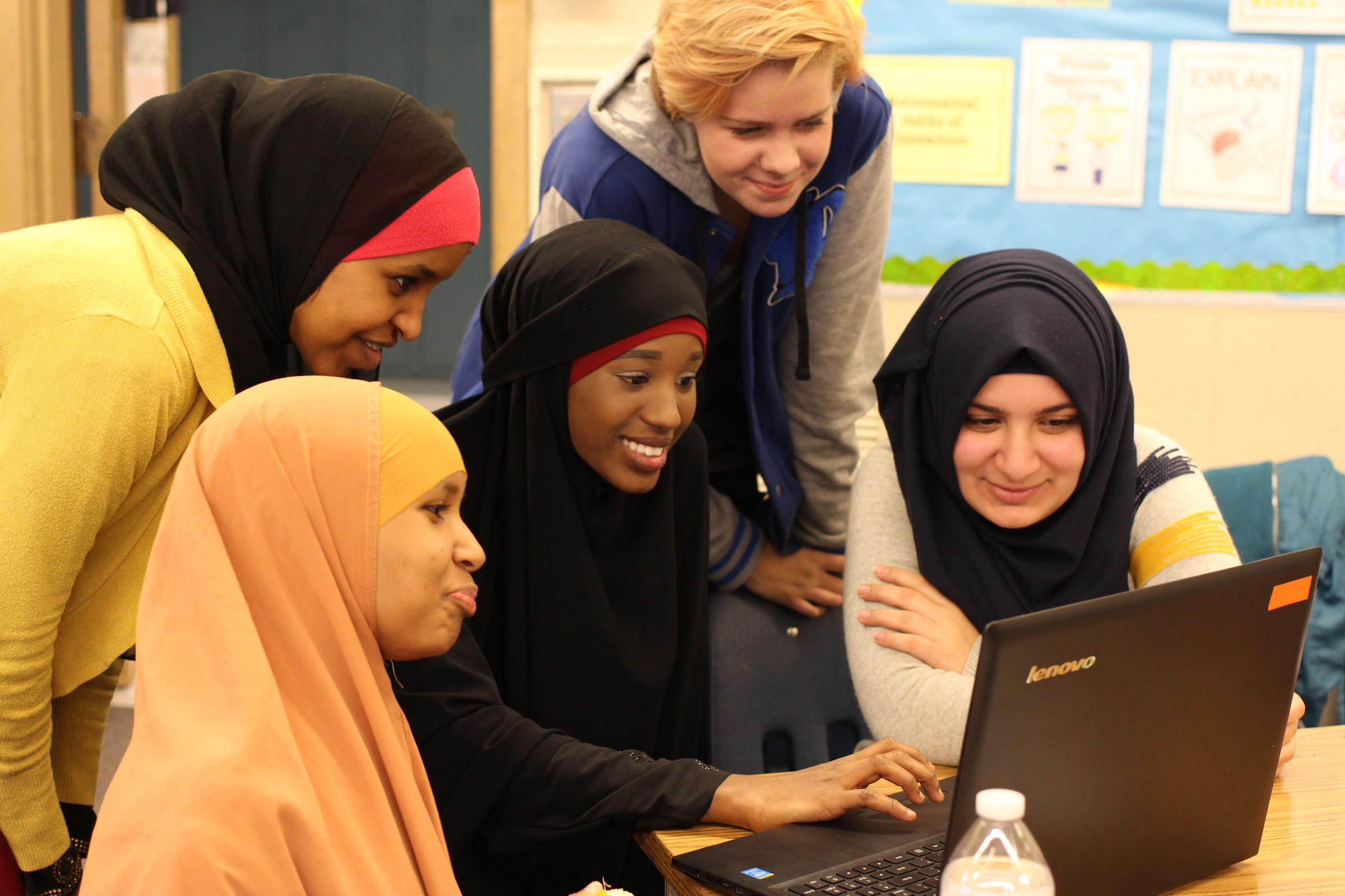 caption: Students huddle around a computer to learn about audio editing during RadioActive's 6-week podcasting workshop in Kent.