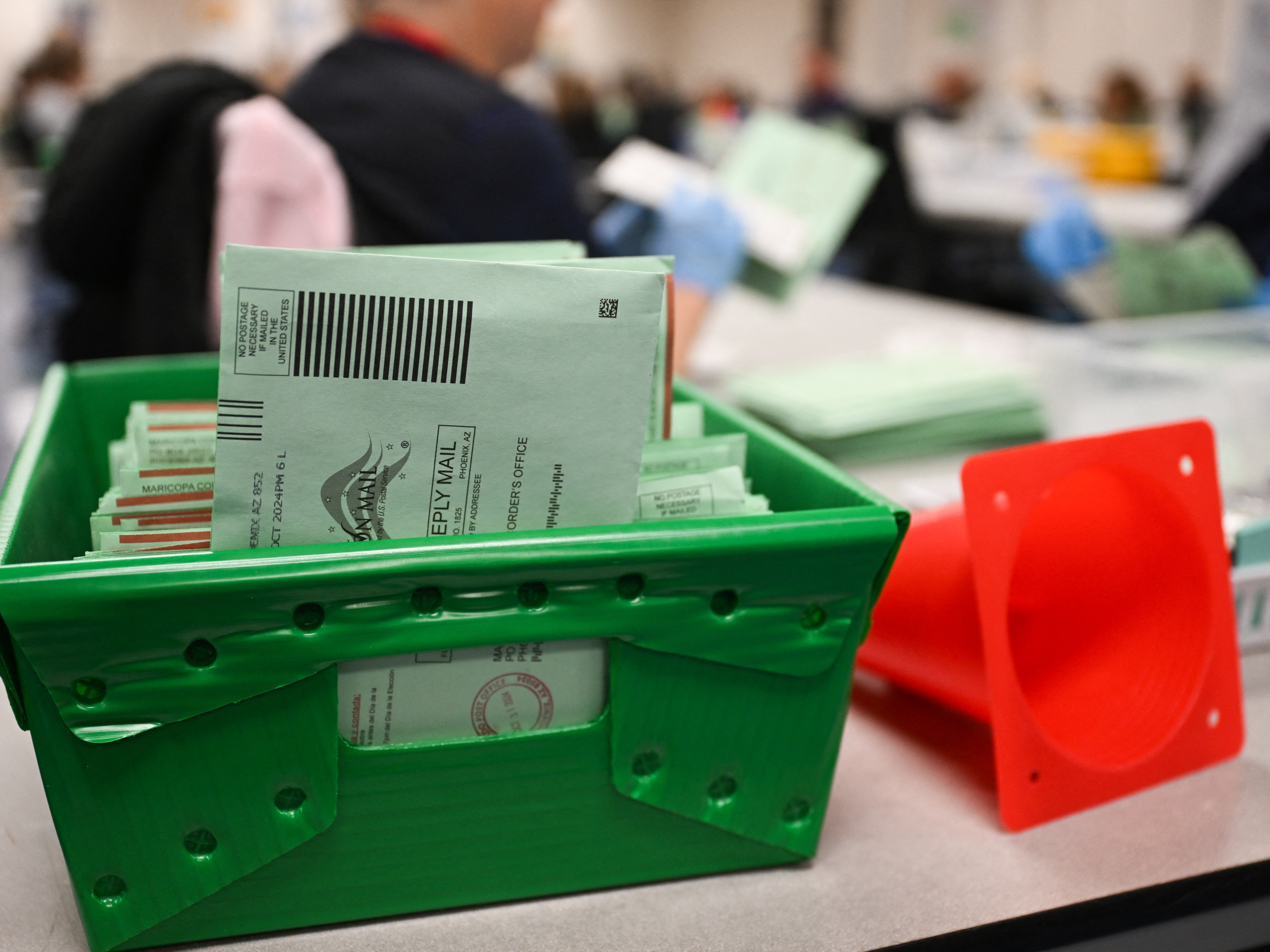 caption: The USPS Election Mail logo is displayed as ballots sit in a tray inside the Maricopa County Tabulation and Election Center (MCTEC) on Election Day, Nov. 5, in Phoenix, Arizona.