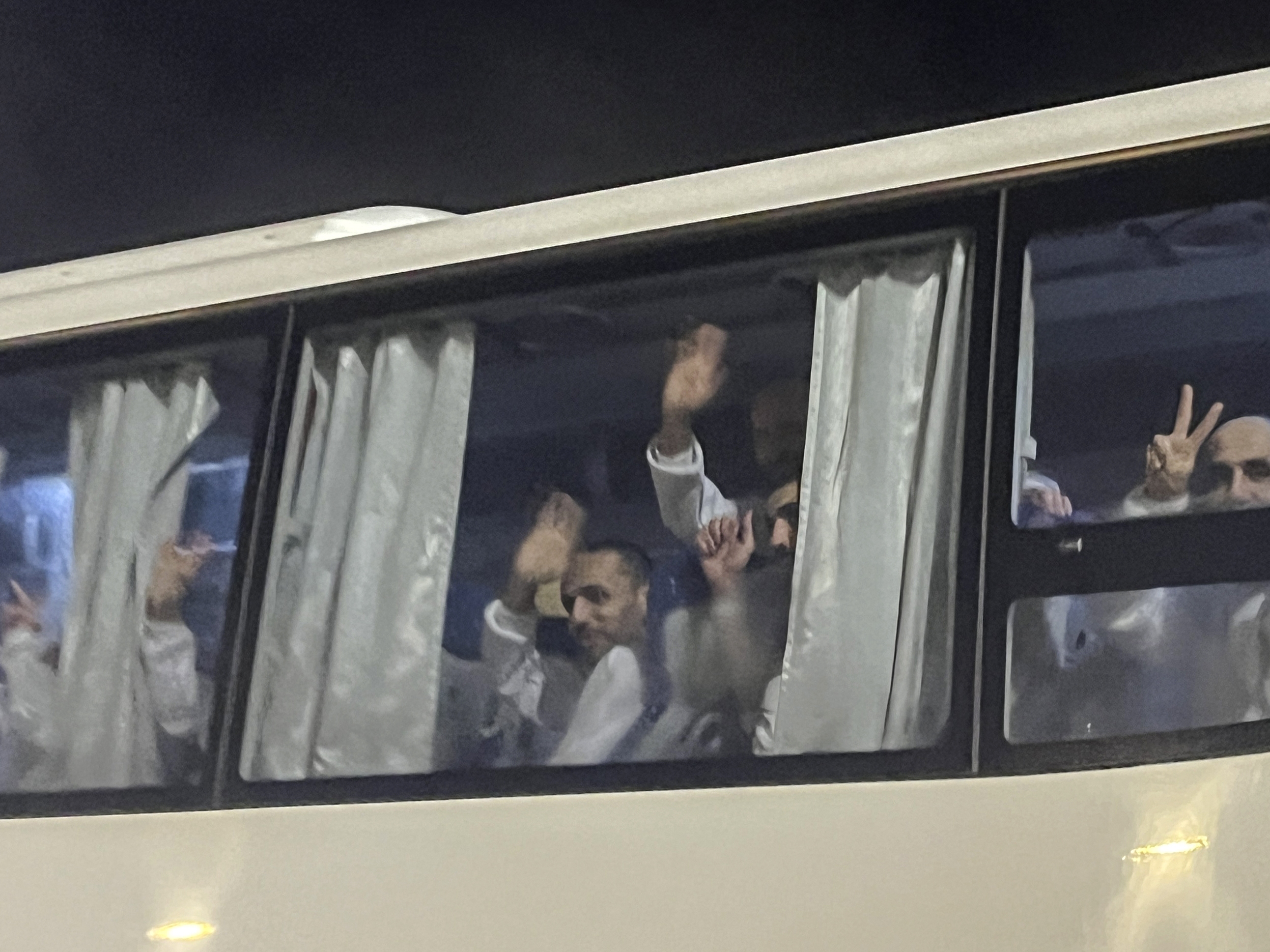 caption: Palestinian prisoners deported outside the Palestinian Territories wave after being released from Israeli prison, following a ceasefire agreement between Israel and Hamas, as they arrive at the Egyptian side of the Rafah border crossing between Egypt and the Gaza Strip, Feb. 27.