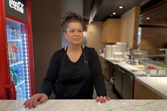 caption: Leyla Farange stands behind the counter at Gyros Place in the food court under Twitter's old offices at Century Square across 4th Avenue from Westlake Park.