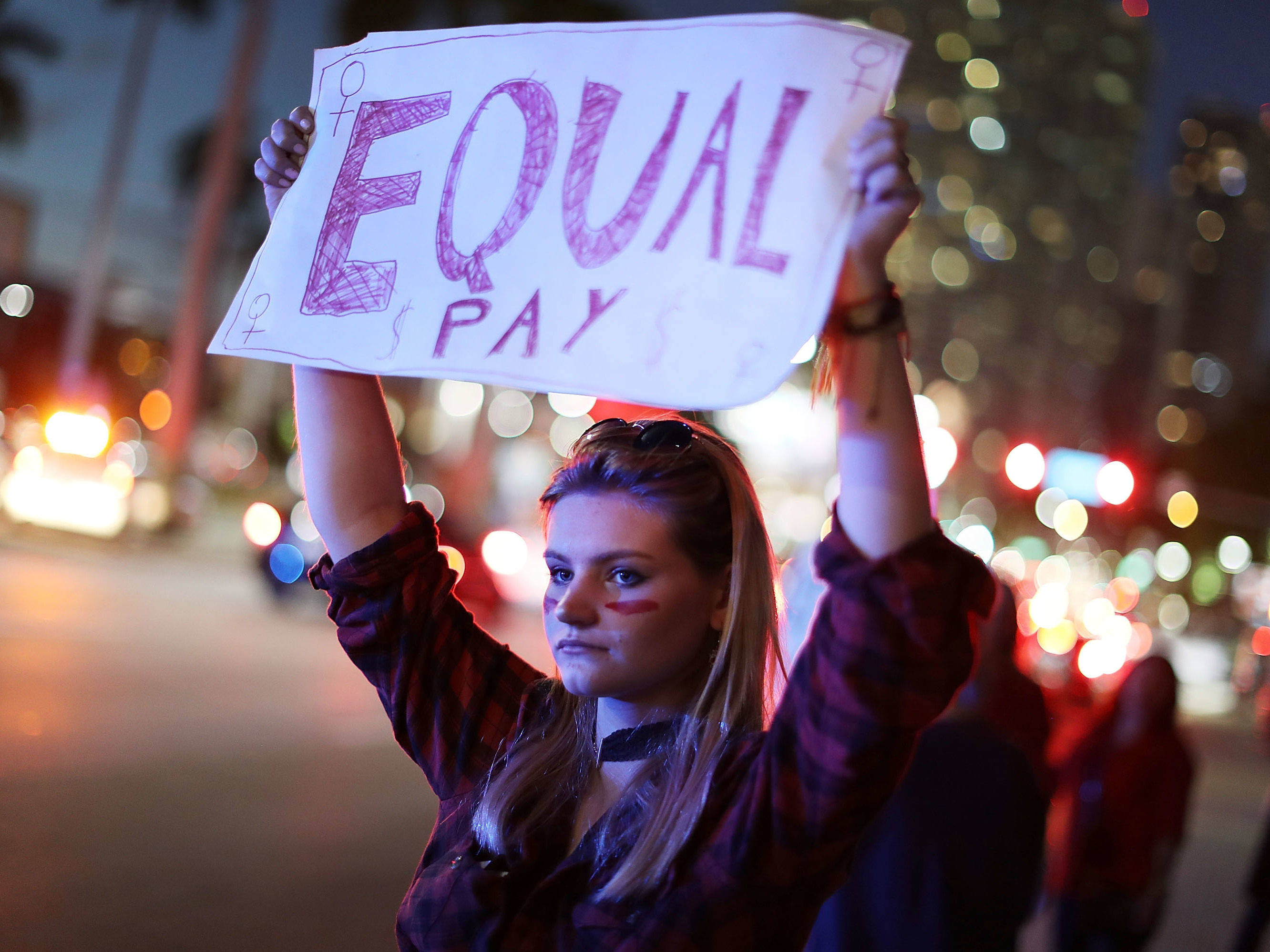 caption: Clarissa Horsfall joins with others during "A Day Without A Woman" demonstration on March 8, 2017, in Miami. Employment attorneys say they've seen a spike in pay-disparity cases.