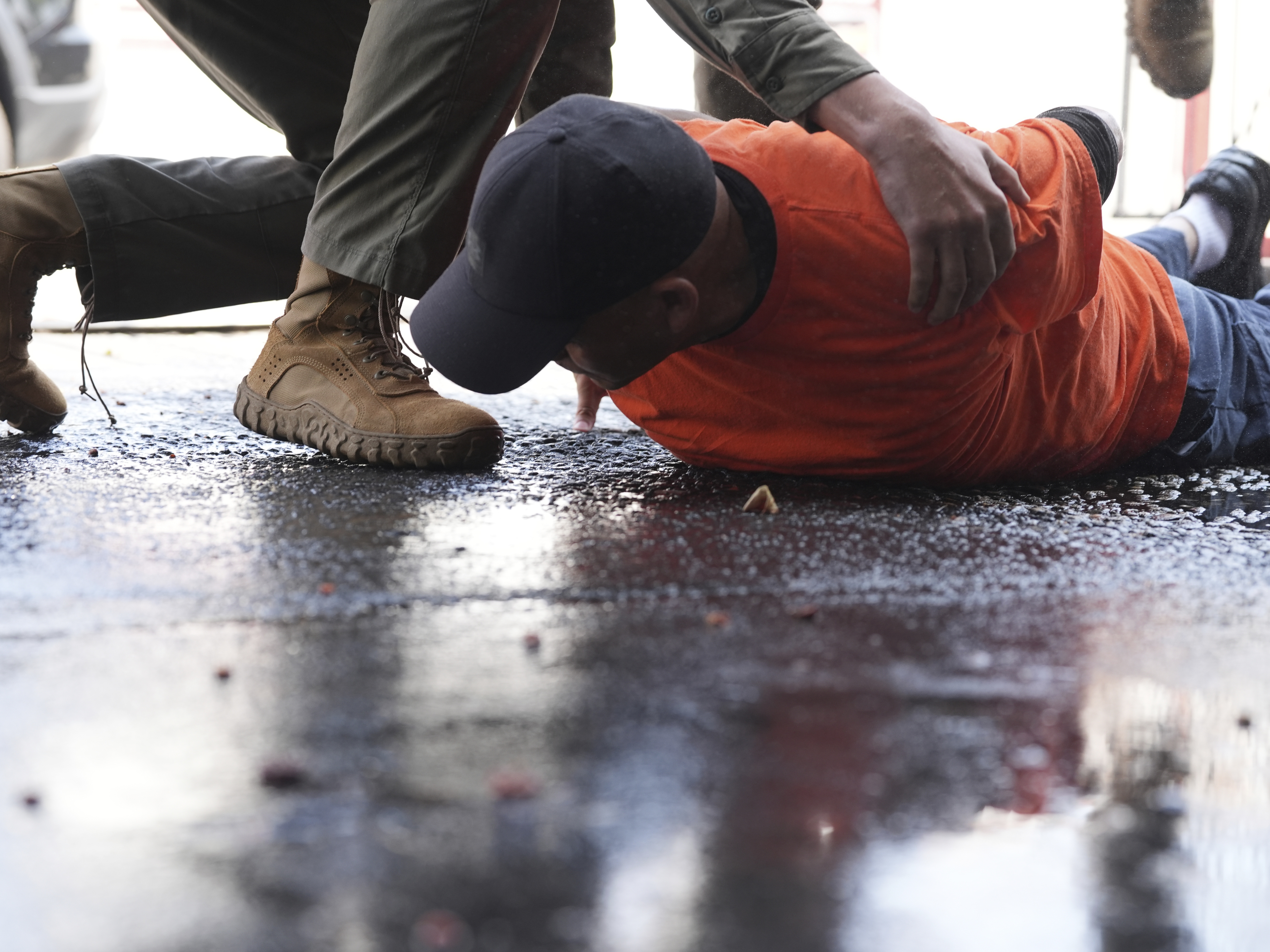 caption: A man is detained by immigration agents at a car wash on Aug. 15 in Montebello, Calif.