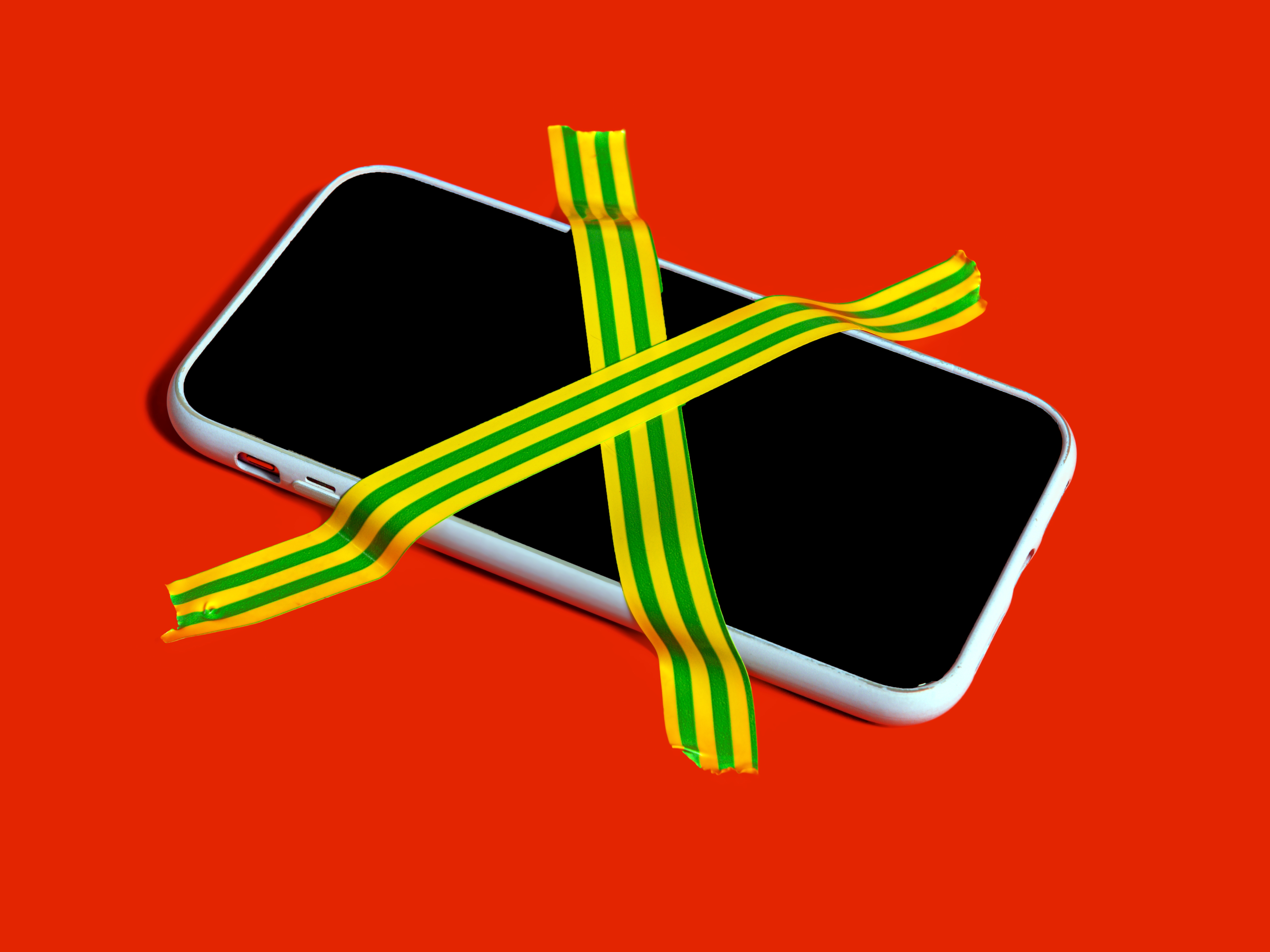 Colorful still life of a banned smartphone with cross-hatched adhesive tape symbolizing digital detox and mindfulness