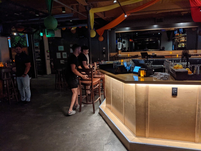 caption: Staff at Union Bar in Seattle put chairs back at the bar after Washington state officially reopened at 12:01 a.m. on June 30, 2021.