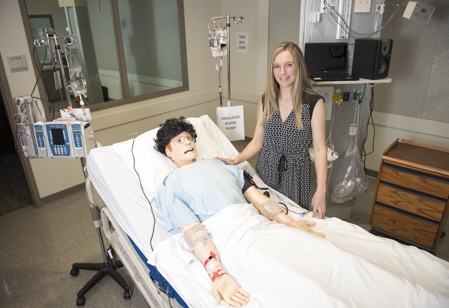 caption: WSU Spokane College of Nursing assistant dean for research Lois James poses beside the lab mannequin that tired nurses interacted with in a recent study.