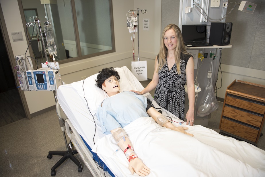 caption: WSU Spokane College of Nursing assistant dean for research Lois James poses beside the lab mannequin that tired nurses interacted with in a recent study.