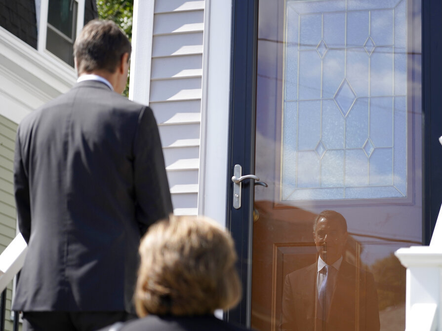 caption: Dan Sideris is reflected in a front storm door Thursday as he and his wife, Carrie Sideris, of Newton, Mass., return to door-to-door visits as Jehovah's Witnesses in Boston. After more than two and a half years on hiatus due to the coronavirus pandemic, members are reviving a religious practice that the faith considers crucial and cherished.