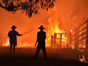 caption: Residents defend a property from a bushfire earlier this month in Taree, north of Sydney.