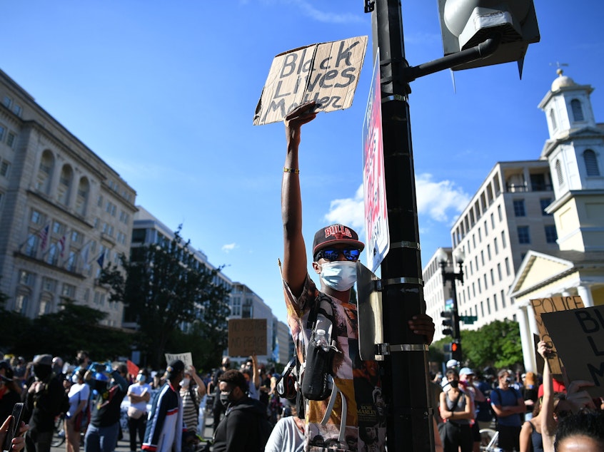 caption: Demonstrators protesting the death of George Floyd hold up placards near the White House on June 1 in Washington, D.C.