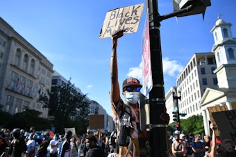 caption: Demonstrators protesting the death of George Floyd hold up placards near the White House on June 1 in Washington, D.C.