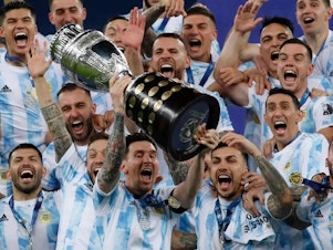 caption: Argentina's Lionel Messi celebrates with the trophy after beating Brazil 1-0 in the Copa America final soccer match at Maracana stadium in Rio de Janeiro, Brazil, Saturday, July 10, 2021. Messi and Argentina will try to win their third straight major title when they defend their Copa America championship while Brazil hopes 17-year-old Endrick will combine with Vinícius Júnior and Rodrygo for success. (AP Photo/Bruna Prado, File)
