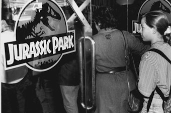 caption: A crowd entering the theater to see <em>Jurassic Park</em>, photographed on October 5, 1993.