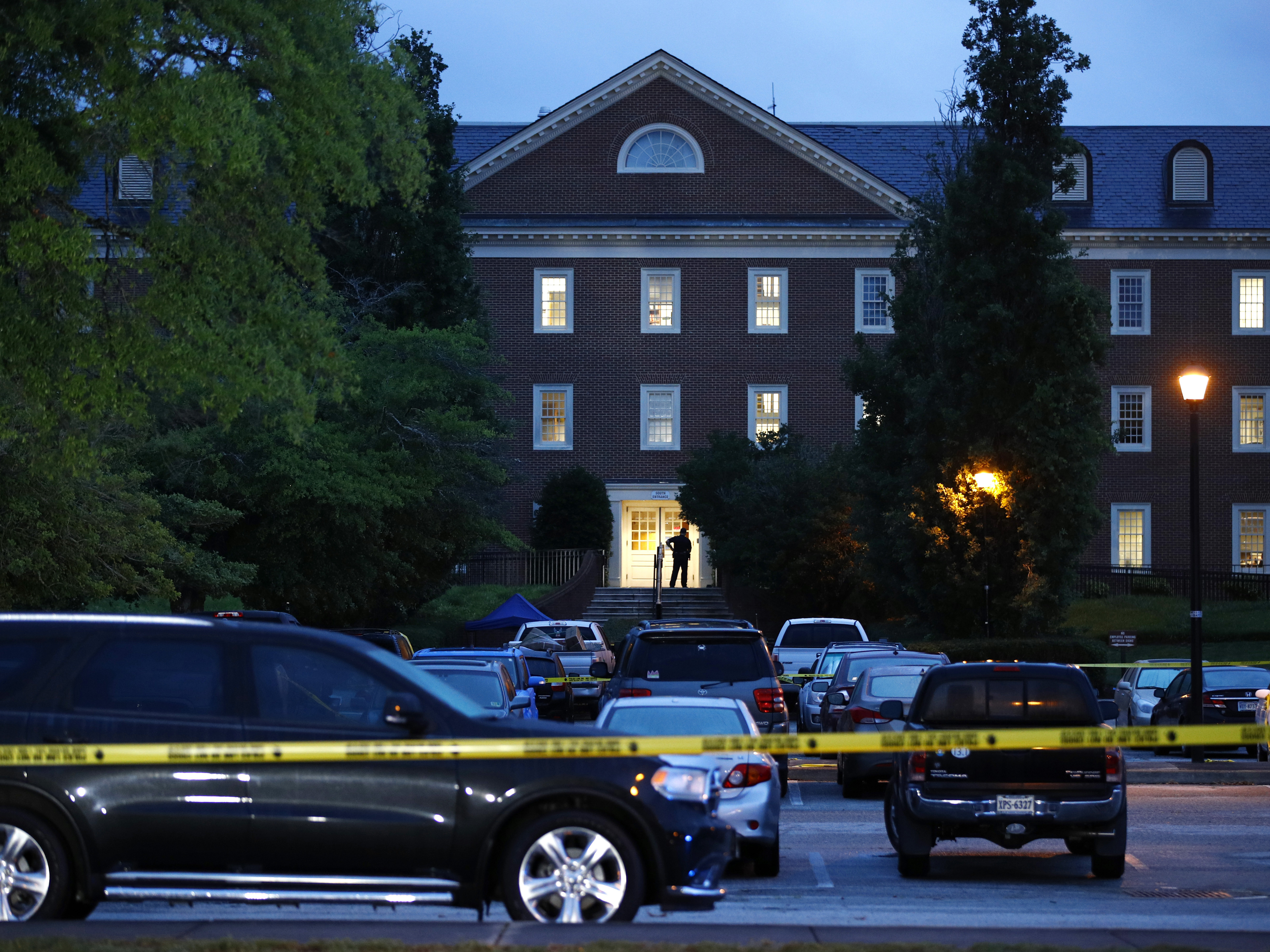 caption: A law enforcement official stands at an entrance to a municipal building that was the scene of a shooting last week in Virginia Beach, Va.