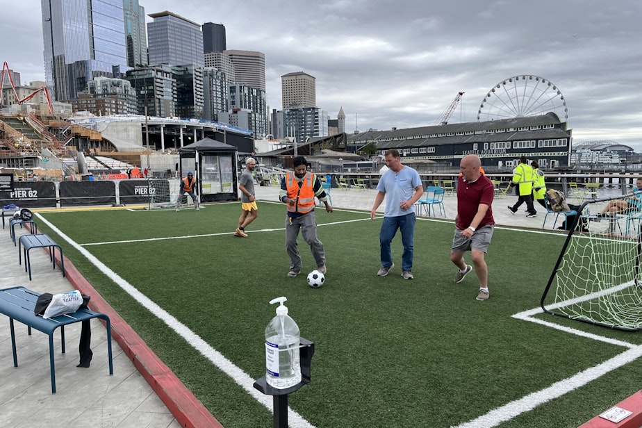 caption: Construction workers and tourists play a game of pickup soccer on Pier 62 in Seattle on September 12, 2023.