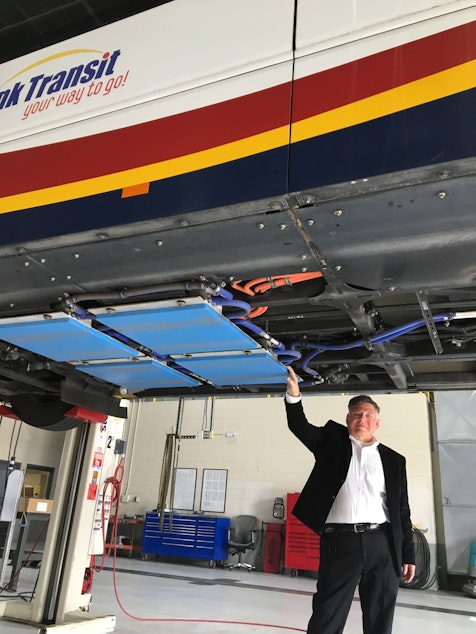 caption: Andy Daga of Momentum Dynamics touches the wireless charging pads on a Link Transit bus in Wenatchee, Washington.