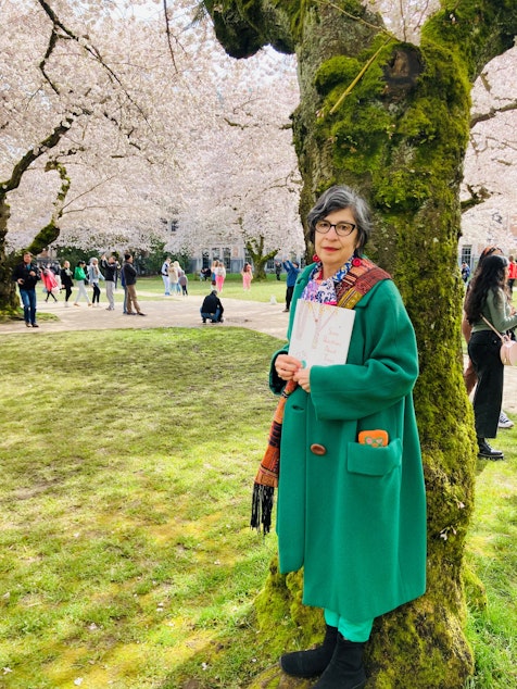 caption: Toni Yuly, author and illustrator of "Some Questions about Trees" stand beneath a cherry blossom tree.