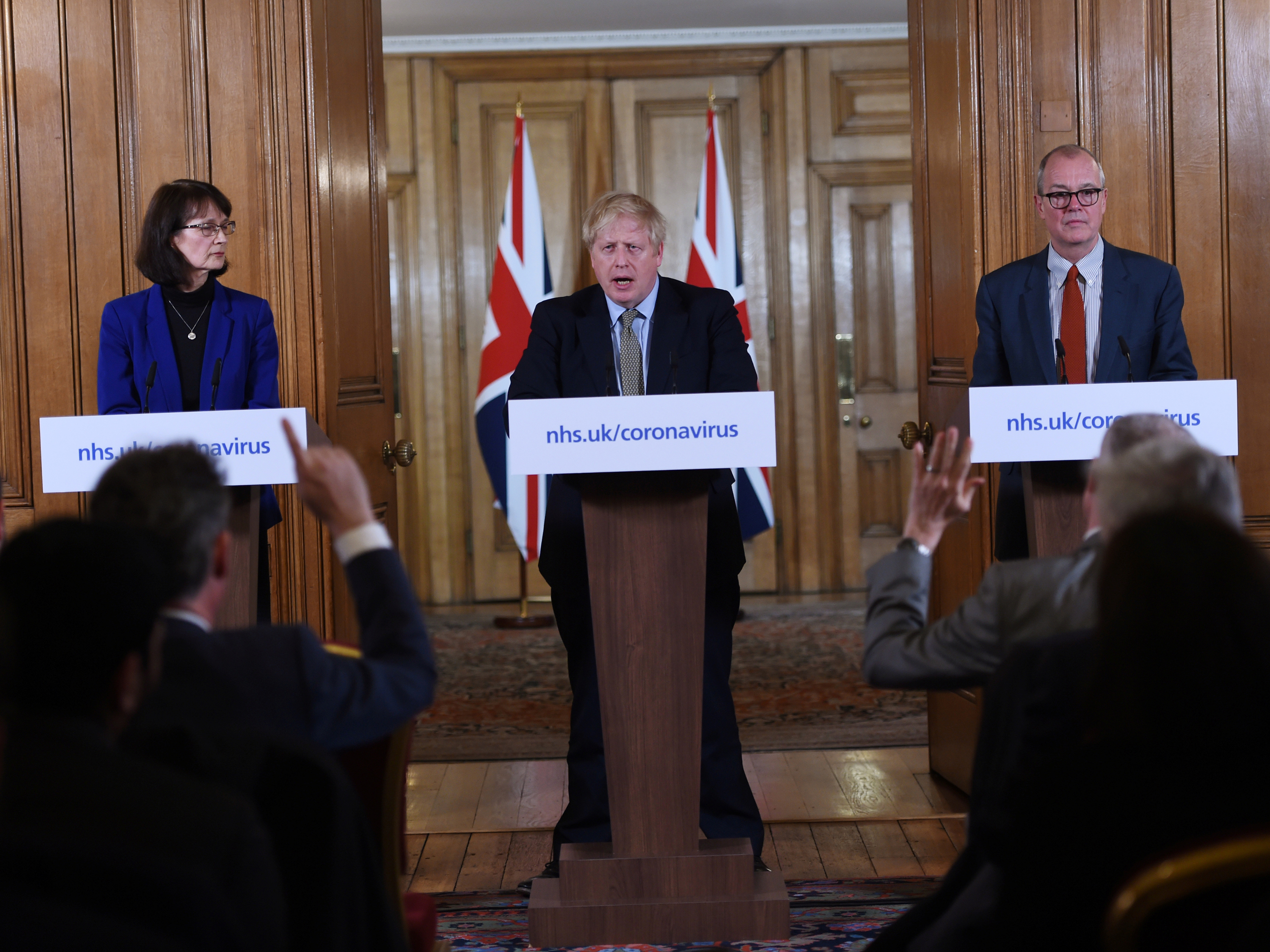 caption: British Prime Minister Boris Johnson, Deputy Chief Medical Officer Dr. Jenny Harries and Chief Scientific Adviser Sir Patrick Vallance at a March news conference on the pandemic. That month, Harries stated that the World Health Organization recommendation for all countries to test extensively was meant more for lower income countries than for wealthy nations. The U.K. later changed its view.