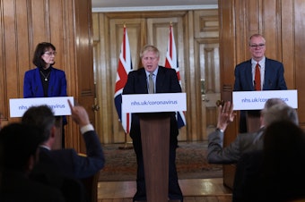 caption: British Prime Minister Boris Johnson, Deputy Chief Medical Officer Dr. Jenny Harries and Chief Scientific Adviser Sir Patrick Vallance at a March news conference on the pandemic. That month, Harries stated that the World Health Organization recommendation for all countries to test extensively was meant more for lower income countries than for wealthy nations. The U.K. later changed its view.