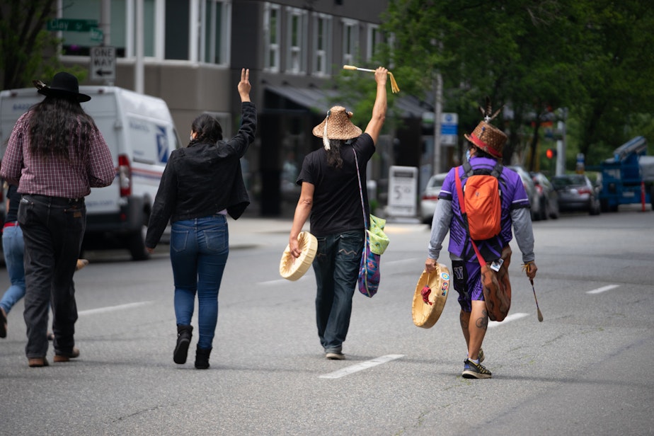 caption: A group of singers and drummers lead the way to Seattle Center from Seattle's Pike Place Market on Saturday, May 22, 2021, in Seattle. 