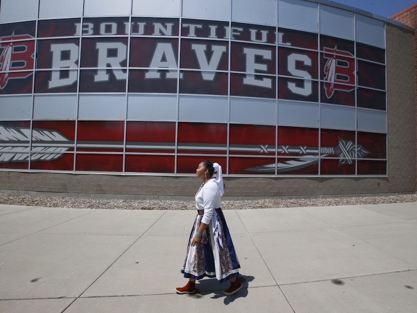 caption: Lemiley Lane, who grew up in the Navajo Nation in Arizona, walks along the Bountiful High School campus during her junior year in 2020 in Bountiful, Utah. The school changed its nickname in 2021 to "The Redhawks."