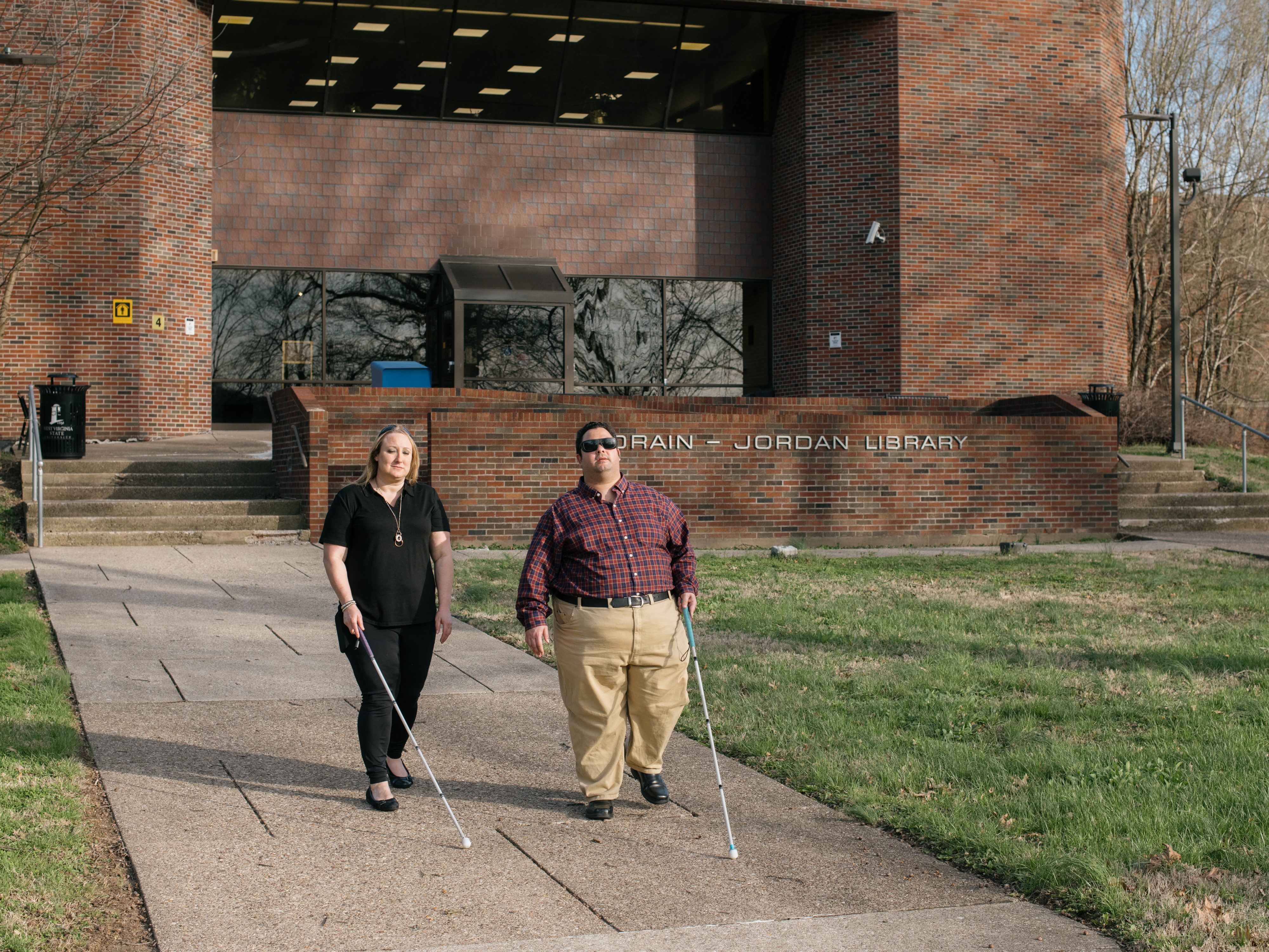 caption: Miranda Lacy and Harold Rogers walk around the campus of West Virginia State University, where both completed undergraduate degrees. They consider the campus a second home because staff there worked hard to make sure their education was accessible. Now, they're in a graduate program that they say has failed to make their learning materials accessible and have filed a lawsuit.