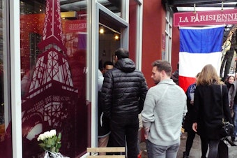 caption: People gather Saturday at La Parisienne bakery in Seattle's Belltown to show support after the terrorist attacks in Paris.