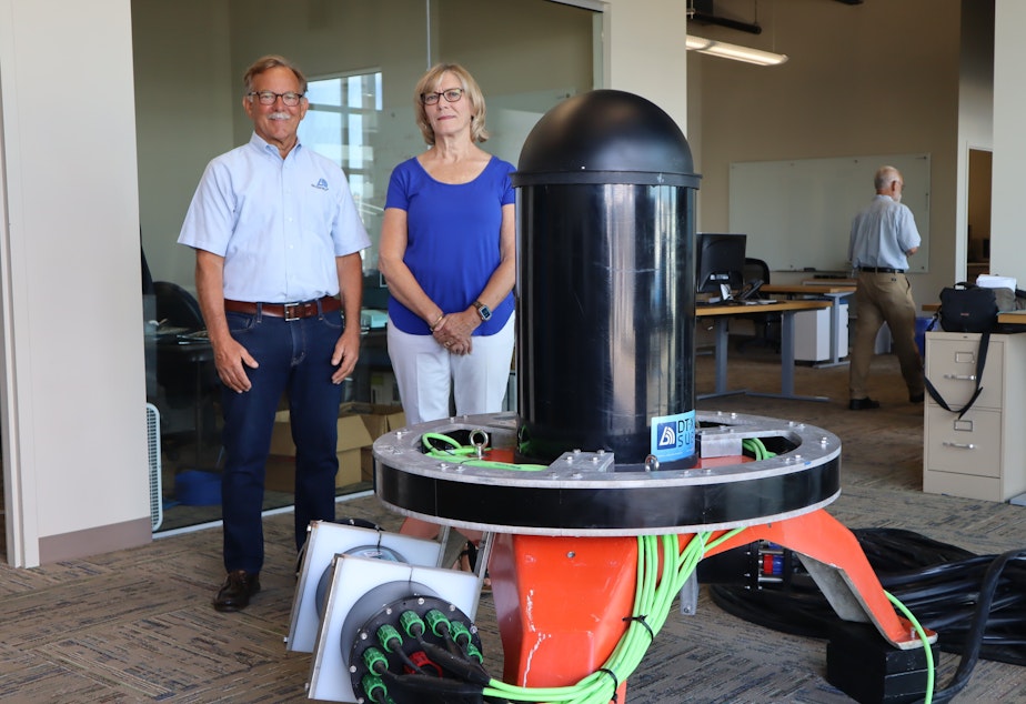 caption: Tim and Bev Acker, CEO and CFO respectively of Biosonics, stand beside the Seattle company’s new ocean-bottom sonar device, which is designed to facilitate marine energy permitting by identifying and tracking nearby sea life.