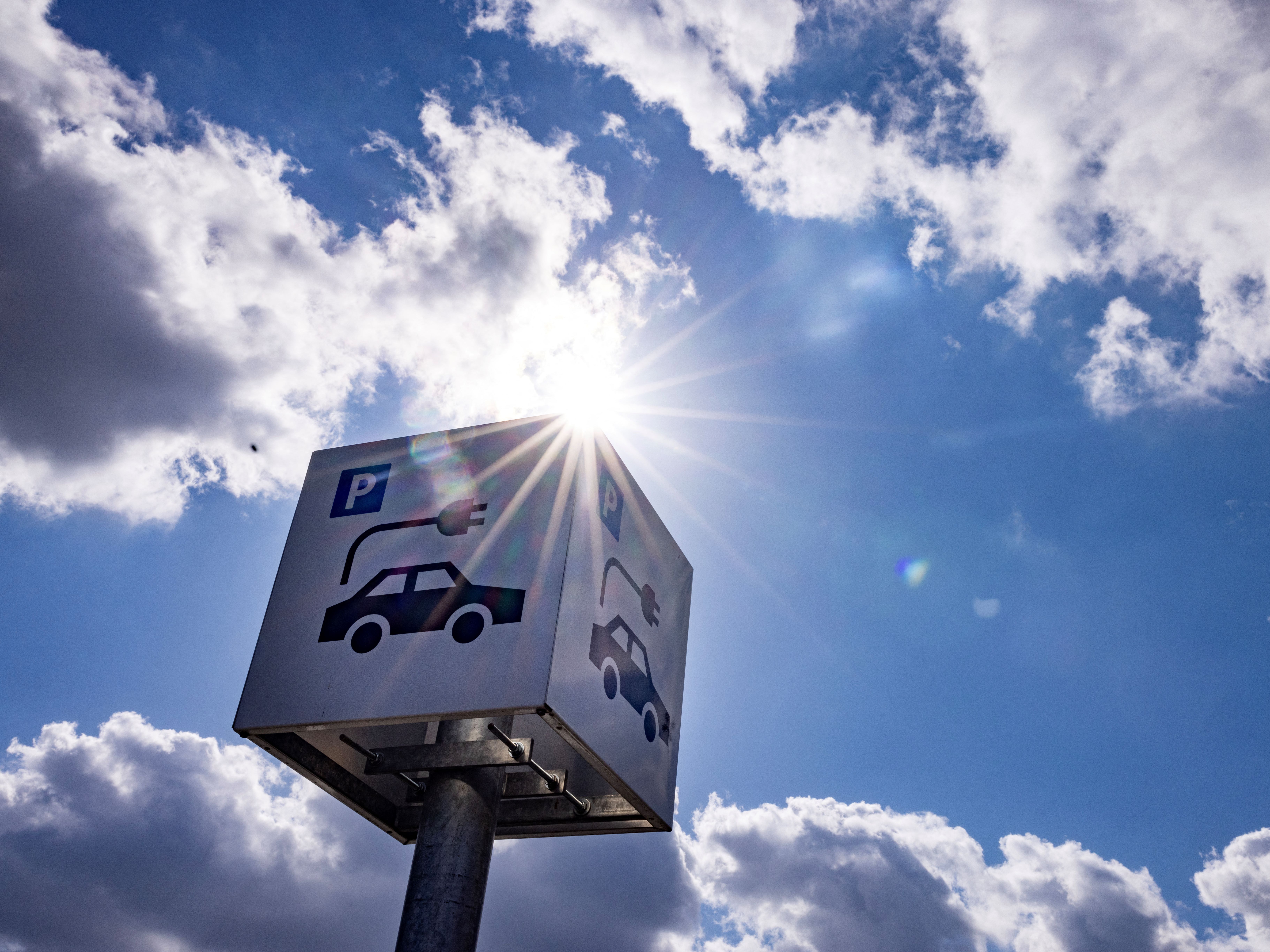 caption: A sign offers parking and charging facilities for electric cars at a retail park in Berlin in 2023. Evidence from the oldest generation of electric vehicles suggests their batteries are lasting longer than was expected in the early days of the EV industry.