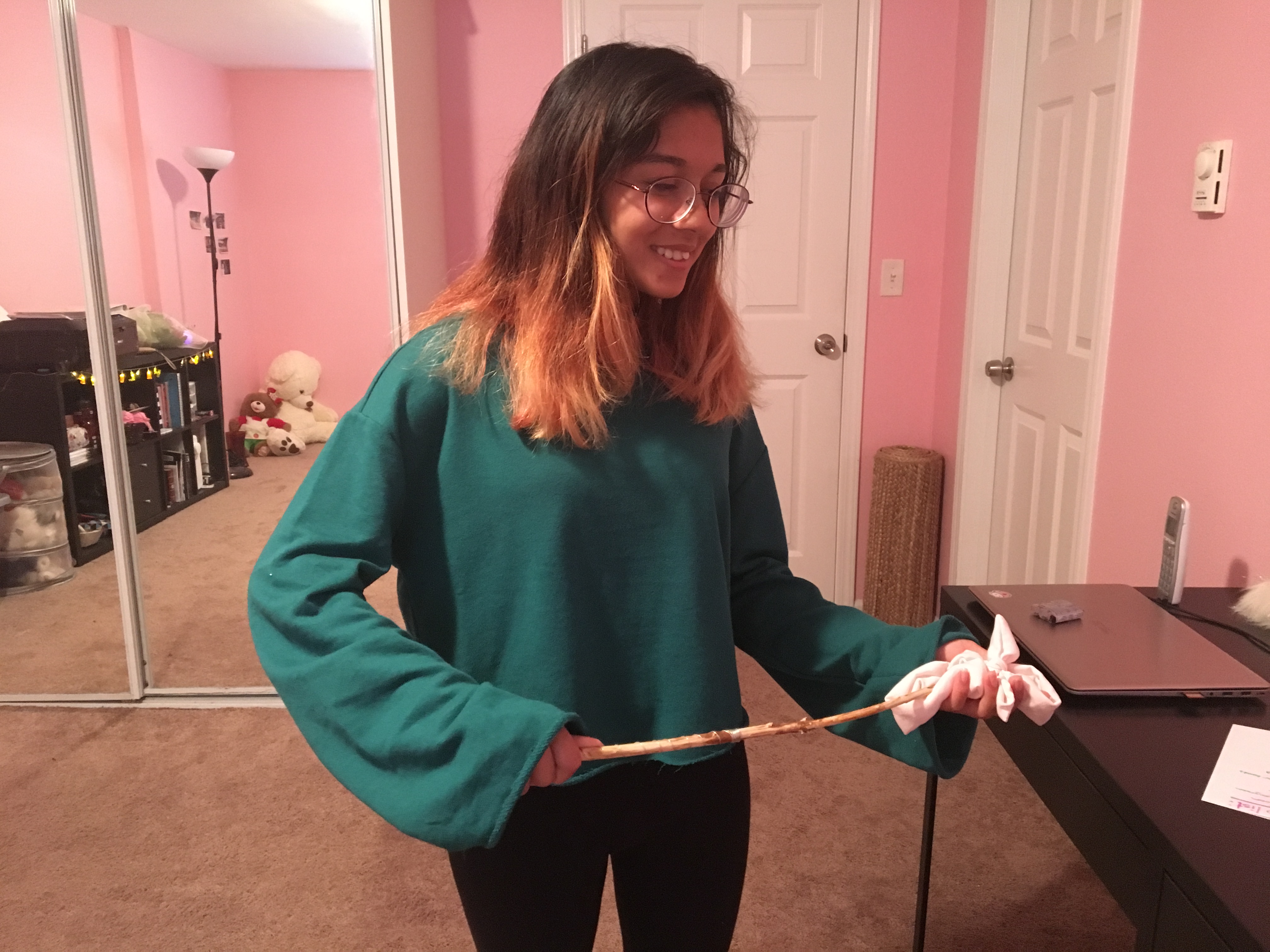caption: Arya Barlinge uses her homemade wand, crafted from an apple tree, to demonstrate how she would channel energy to the headband she holds.