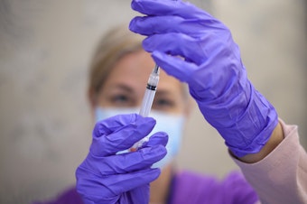 caption: A nurse draws a vaccine dose from a vial of Moderna's COVID vaccine at the Cameron Grove Community Center in Bowie, Md., in March.