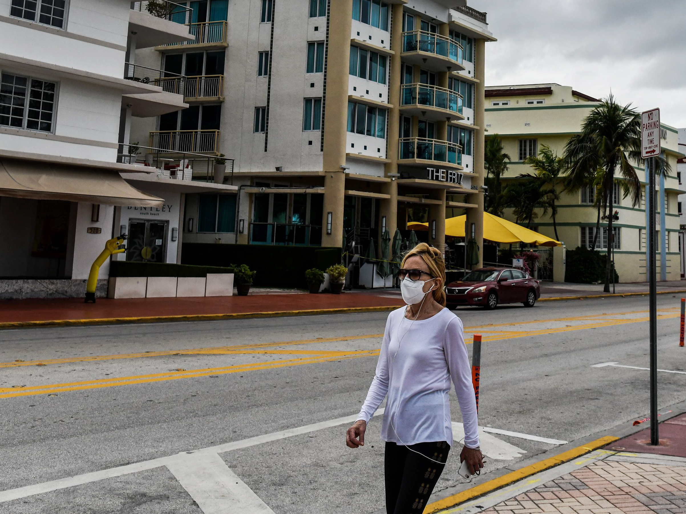 caption: A woman wearing a face mask walks on the deserted Ocean Drive amid the novel coronavirus pandemic in South Beach, Miami, on May 13. Pandemic war game simulation in the early 2000s foresaw an overwhelmed healthcare industry struggling to respond to unprecedented demand.