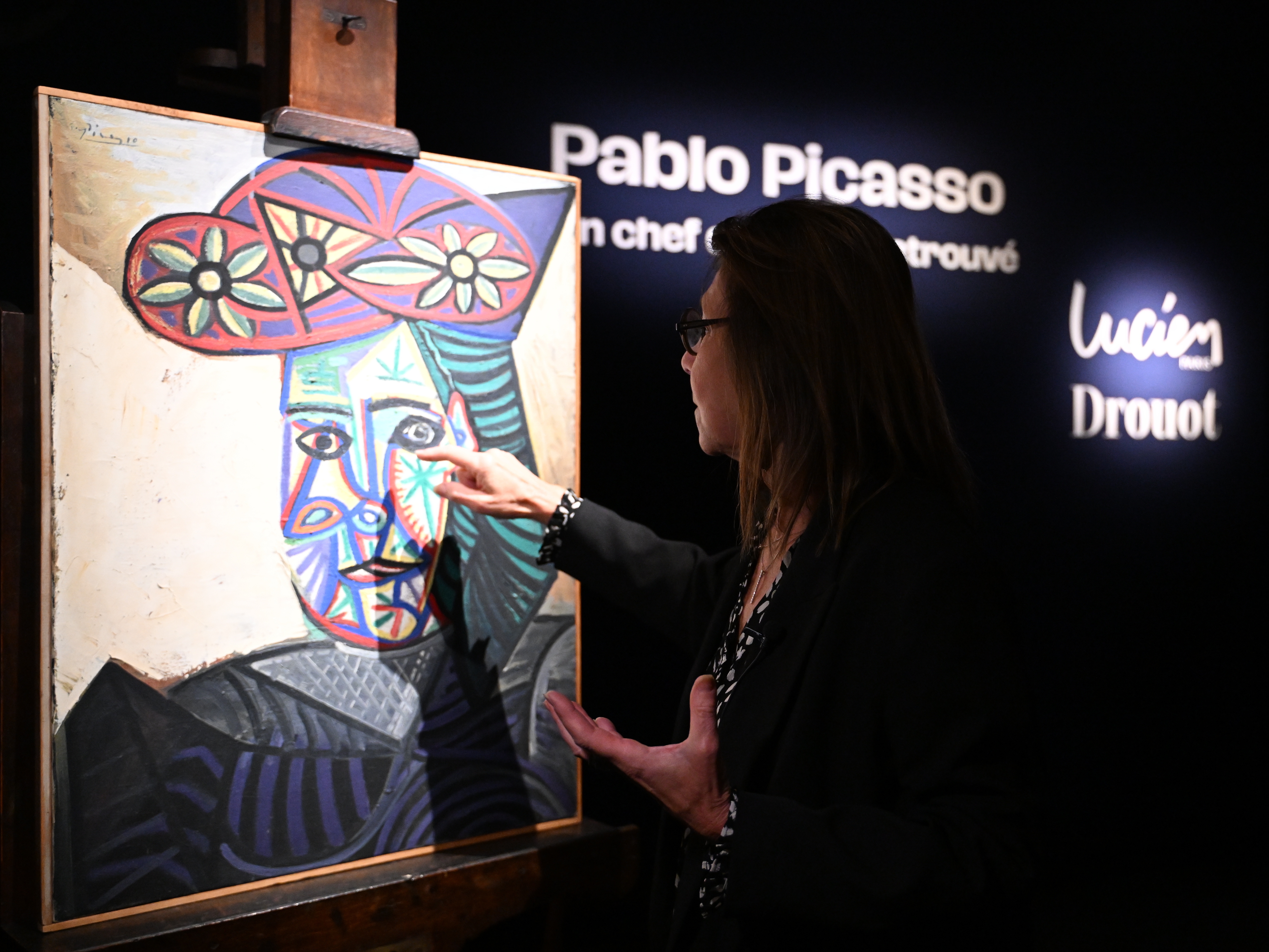 caption: Art expert Agnes Sevestre-Barbe points to a rediscovered Picasso painting "Bust of a Woman in a Flowery Hat," on Wednesday in Paris. The portrait of longtime muse and partner Dora Maar sold Friday at auction for 32 million euros (about $37 million).