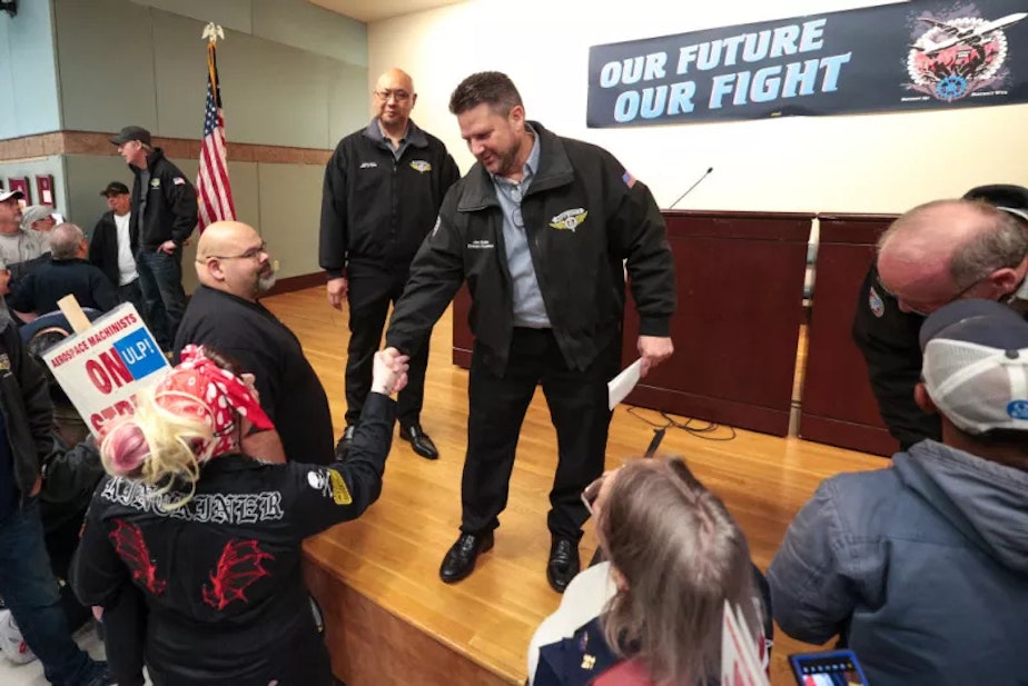 caption: Jon Holden, the president of IAM District 751, shakes hands with Kat Kinckiner, a Boeing tool-room clerk for 15 years, during a strike rally in Seattle, Wash.