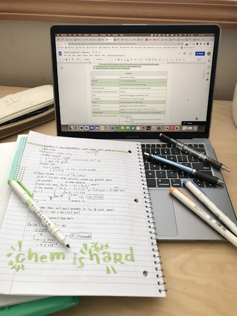 caption: Alayna Ly's desk during her senior year of high school, set up with her laptop full of tabs, her chemistry notebook, and writing utensils. 