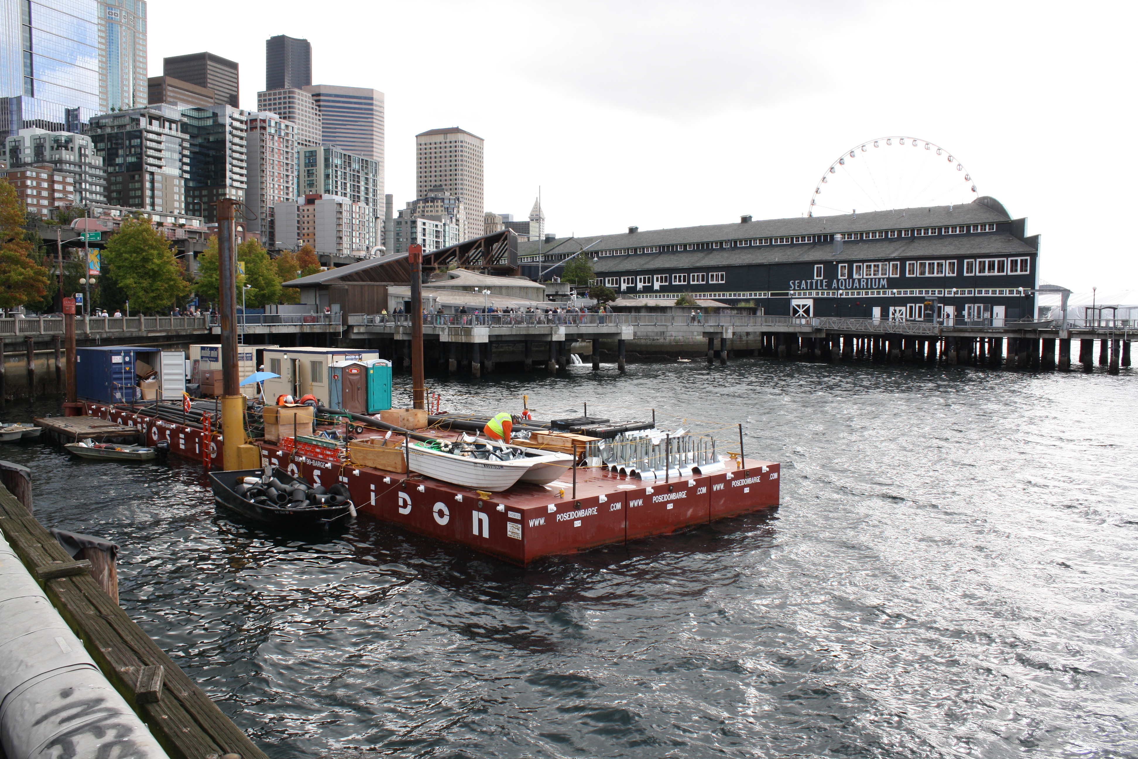 caption: Utilities must be rerouted before Seattle's current seawall comes down. But with no room on the crowded sidewalk to stage construction materials, the job shack for utility workers resides on a barge.
