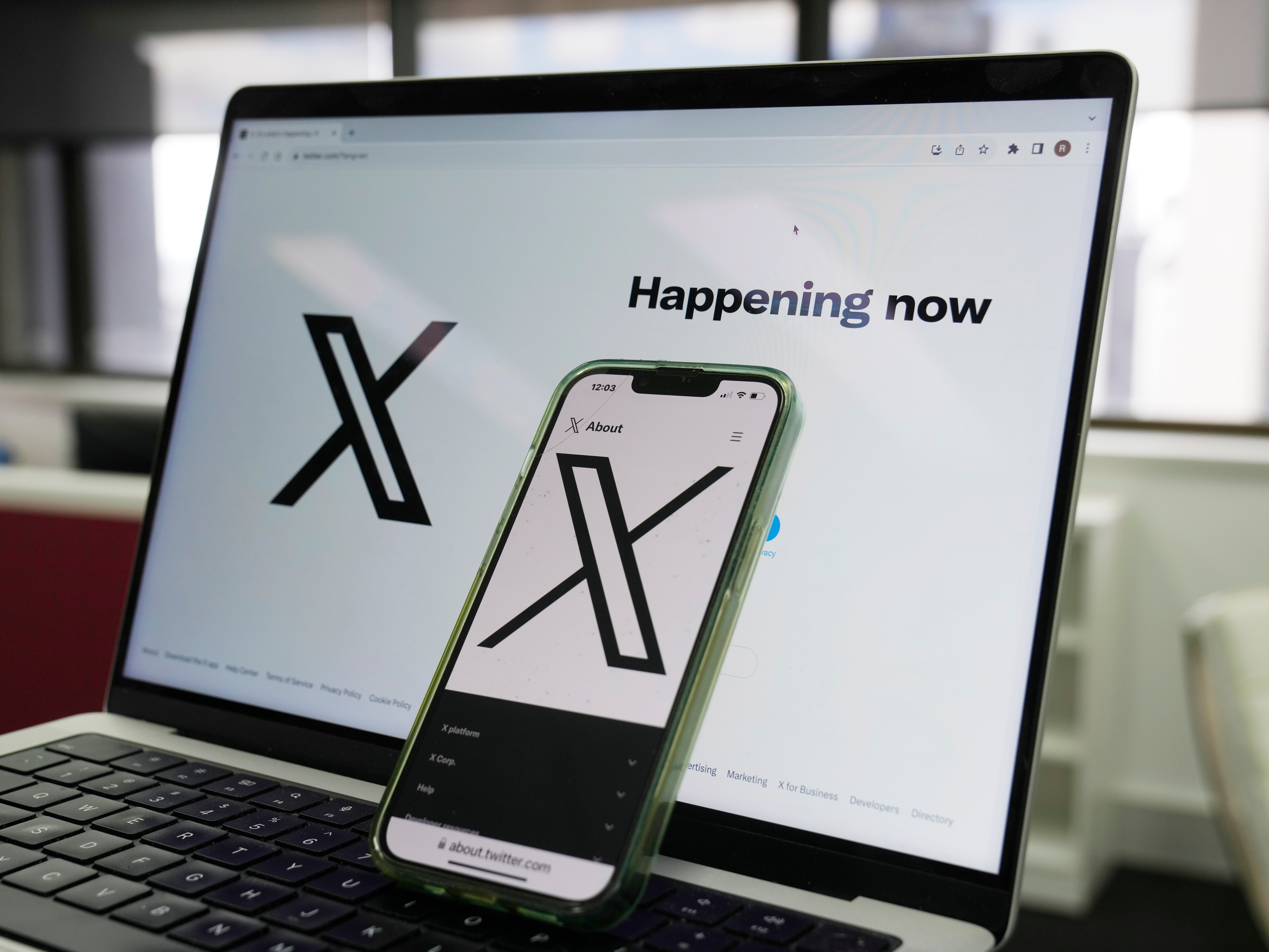 caption: The opening page of X is displayed on a computer and phone, Oct. 16, 2023, in Sydney.