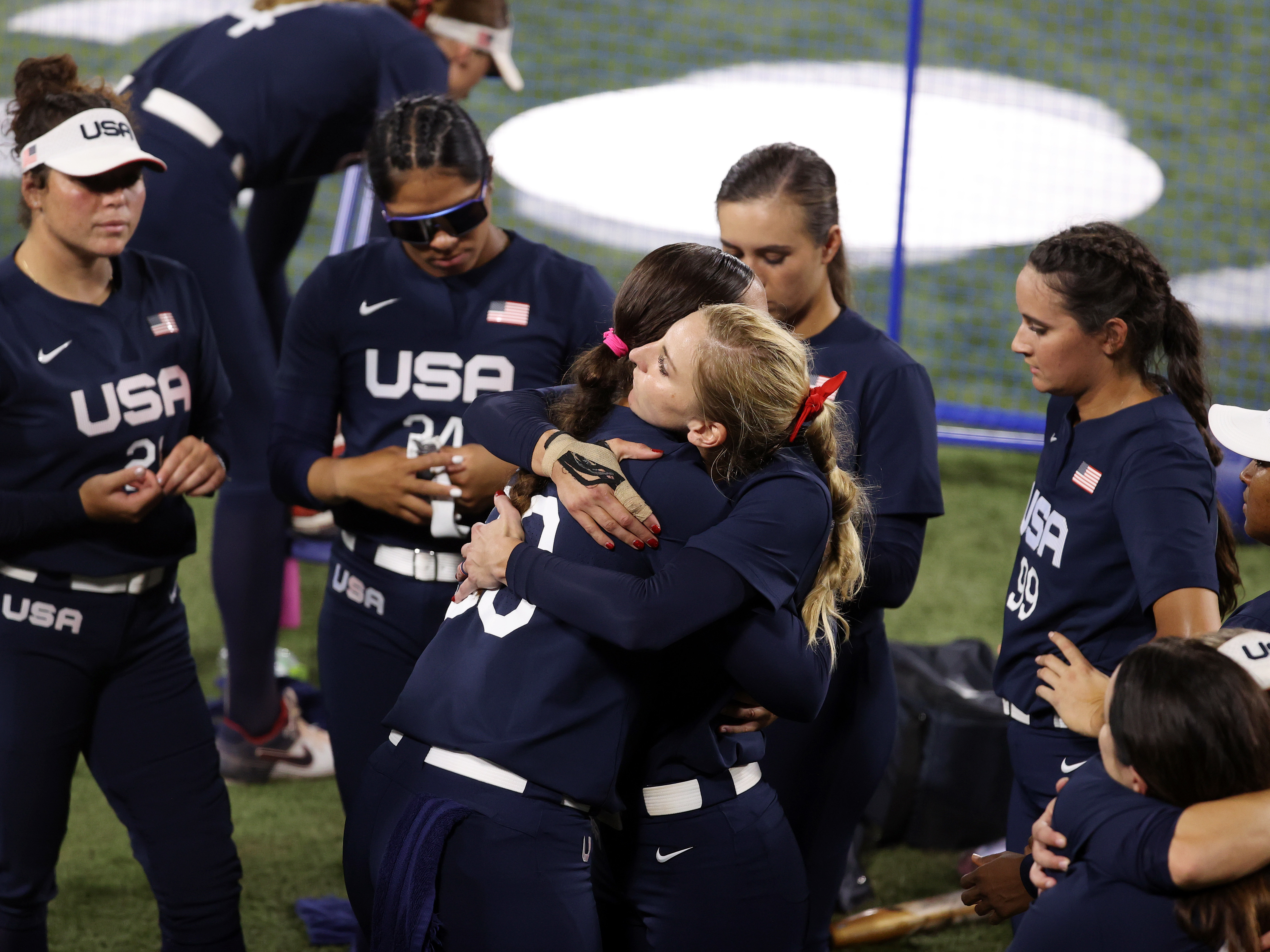 caption: Haylie McCleney #8 hugs Catherine Osterman #38 of Team United States after losing to Team Japan 2-0 in the Softball Gold Medal Game on day four of the Tokyo 2020 Olympic Games.
