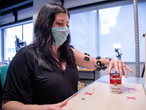 caption: Research participant Heather Rendulic prepares to grasp and move a can of tomato soup at Rehab Neural Engineering Labs at the University of Pittsburgh.