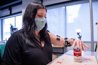 caption: Research participant Heather Rendulic prepares to grasp and move a can of tomato soup at Rehab Neural Engineering Labs at the University of Pittsburgh.