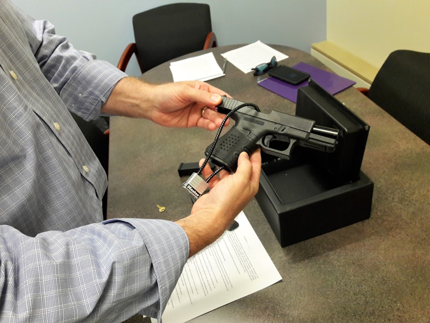 caption: Edmonds City Council President Mike Nelson demonstrates how he uses a safe for his pistol.