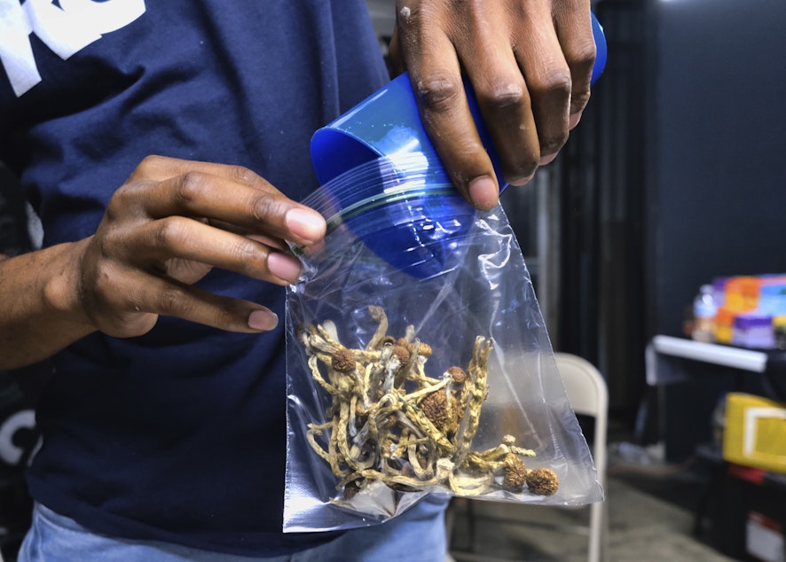caption: In this Friday, May 24, 2019 photo a vendor bags psilocybin mushrooms at a pop-up cannabis market in Los Angeles.